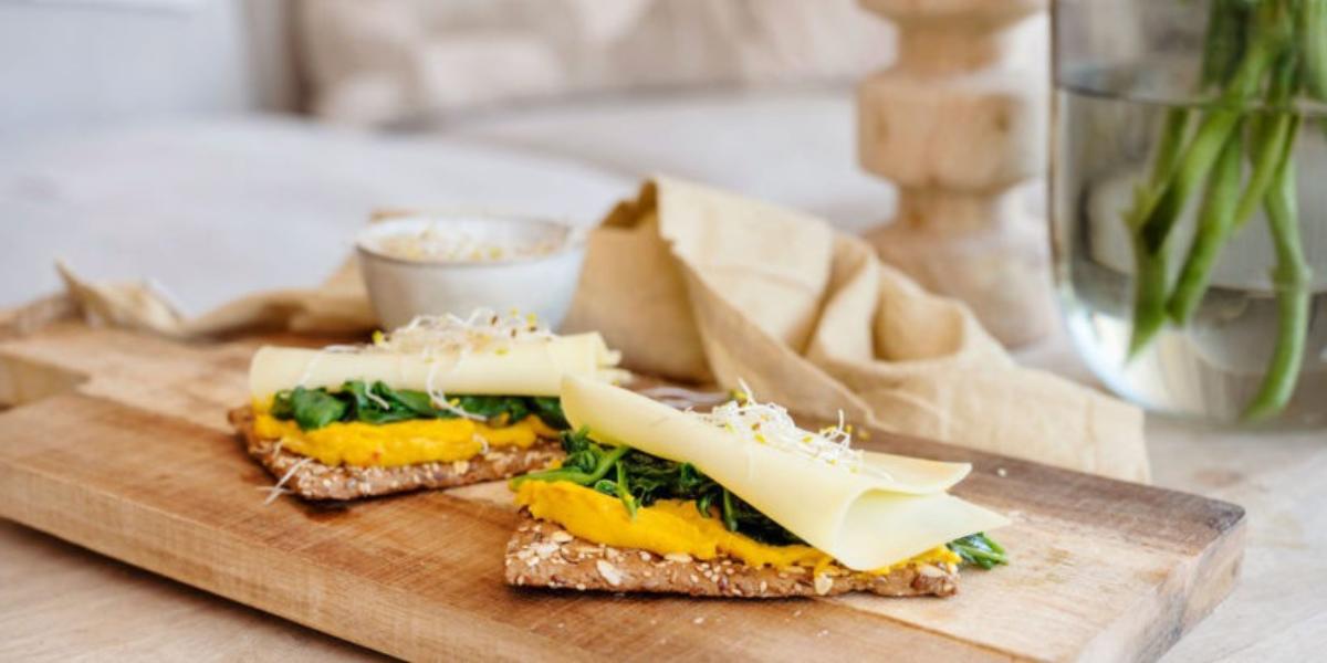 Volkoren crackers met jonge Uniekaas, zoete aardappel hummus, gebakken spinazie en alfalfa