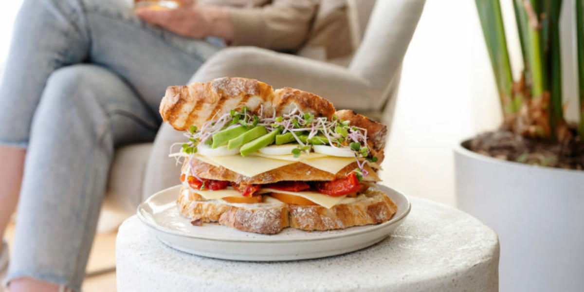 Clubsandwich met Jong belegen Uniekaas mayonaise, gerookte kip, ei, avocado, cherry tomaten en kiemgroenten