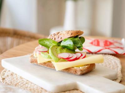 Hard broodje met pompoenpitten, radijs, avocado en veldsla